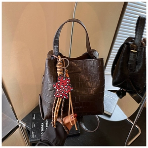 Detailed texture of brown crocodile embossed handbag with a cute heart leopard bear charm