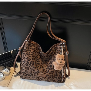 Close-up of leopard print tote bag featuring a leather brand tag and plush bear charm