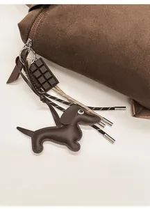 Detail of a brown leather dachshund bag charm with chocolate accessory and braided cord