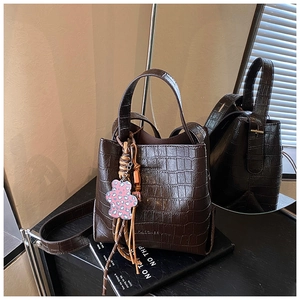 Detail of dark brown crocodile pattern bucket bag with cute bear charm on books