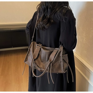 Detail view showing a large brown vintage tote bag worn by a model in a casual setting