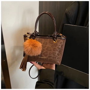 Détail du sac seau à imprimé léopard avec anses en cuir et pompon décoratif