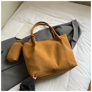 Detail view of large mustard yellow leather tote bag with matching mini zipper pouch