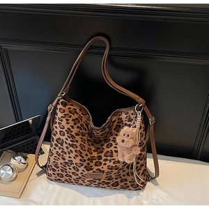 Detailed shot of leopard print hobo bag with adjustable brown strap and plush bear charm
