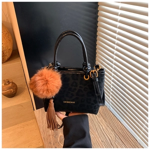 Détail du sac seau à imprimé léopard noir avec pompon marron et glands décoratifs
