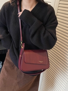 Retro burgundy leather crossbody bag with woven flap detail shown on a female model
