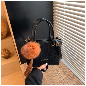 Détail d'un sac léopard avec pompon orange et bandoulière amovible en cuir synthétique