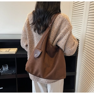 Detail of coffee brown large tote bag with smooth matte texture on model shoulder