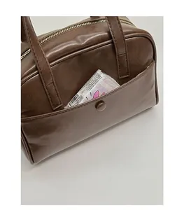 Detail of dark brown leather bowling bag showing front magnetic pocket for easy storage