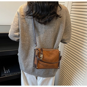 Detailed close-up of brown quilted crossbody bag with golden studs and leather strap