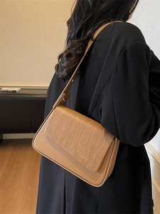 Chic camel brown underarm shoulder bag with textured leather flap shown on model