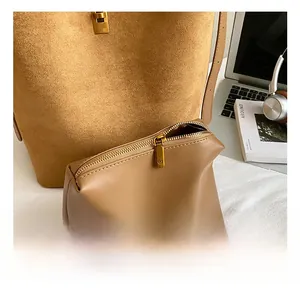Detailed close-up of brown suede tote bag with matching leather pouch and bronze hardware