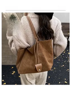 Detail of vintage brown suede tote bag featuring metallic snap button charm on strap