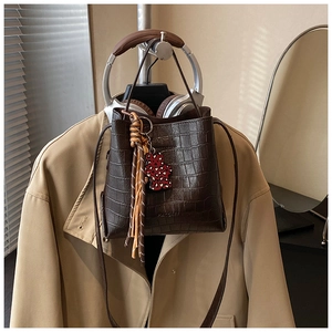 Detail of dark brown croc-embossed bucket bag with MATCHES logo and leopard charm