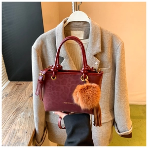 Détail du sac à main bordeaux avec texture léopard, pompon décoratif et franges en cuir