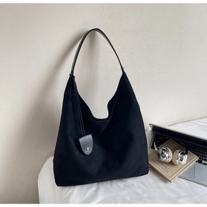 Detail of a black matte leather hobo bag for women with minimalist curved charm accessory