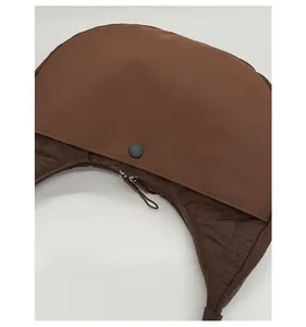 Dettaglio posteriore della borsa a mezzaluna marrone con bottone a pressione e zip