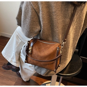 Close-up of brown vintage crossbody bag with diamond quilted stitching and gold hardware