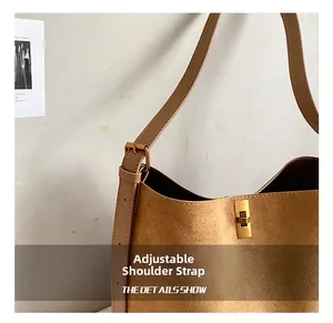 Detail of adjustable leather strap and gold-tone hardware on dark brown suede tote bag