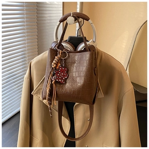 Detail of dark brown crocodile embossed bucket bag with a leopard print bear charm