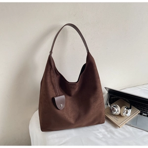 Detail of dark brown suede hobo bag with matching mini pouch on a desk with a laptop