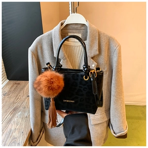 Détail du sac seau noir à motif léopard avec pompon marron et logo doré élégant