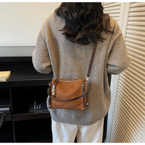 Brown quilted crossbody bag with gold buckle shown on a model in a casual outfit