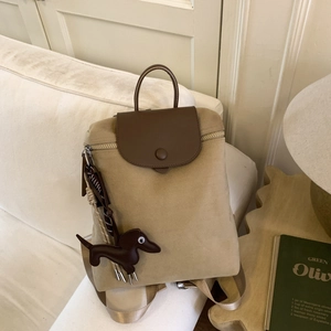 Detail of high-density canvas backpack with brown leather trim and a cute dachshund charm