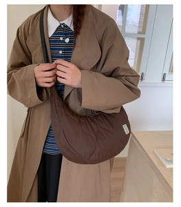Dettaglio di una borsa a mezzaluna marrone trapuntata con cuciture a onda e texture