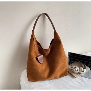 Detailed texture of caramel suede hobo bag with dark brown leather strap in a home setting