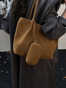 Caramel large tote bag with matching small pouch worn over a grey wool coat