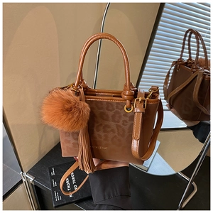 Détail du sac à main léopard avec pompon en peluche et logo embossé en surface