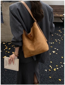 Outdoor street style shot showing side view of the brown suede bucket bag on a model