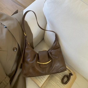 Detail of dark brown leather hobo bag with gold curved buckle and dual strap options