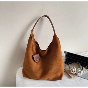 Close-up of caramel suede tote bag with leather straps and decorative mini pouch