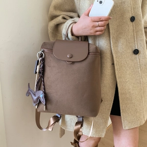 Close-up of brown canvas backpack with leather flap and cute horse charm detail