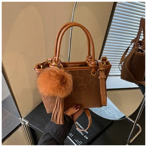 Gros plan du sac seau en cuir marron avec motif léopard et breloque à pompon