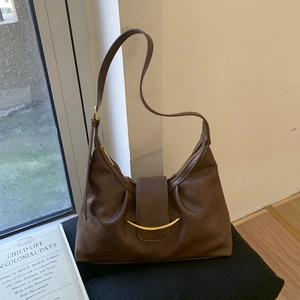 Detail of soft brown leather shoulder bag with golden metallic buckle and adjustable strap