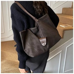 Close-up of a large coffee-colored suede tote bag featuring slim leather straps