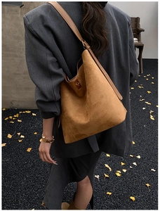 Brown suede bucket bag with leather strap shown from behind on a model outdoors