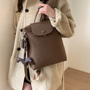 Brown nylon backpack detail featuring a leather flap and brown dachshund charm