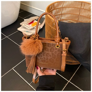 Détail d'un sac à main léopard avec pompon en fausse fourrure et décor de franges