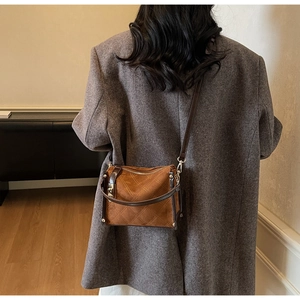 Brown suede crossbody bag with diamond quilting shown on a grey tweed jacket