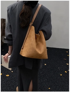 Detail of caramel suede bucket bag with adjustable leather strap worn by a model