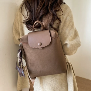 Detail view of large dark brown nylon travel backpack with leather charm on back