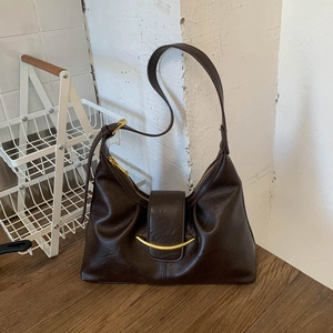 Detail view of the dark brown semi-moon shoulder bag with glossy lychee grain and gold buckle