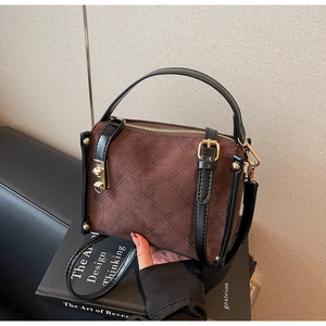 Detail of brown suede crossbody bag featuring quilted stitching and gold hardware accents