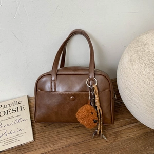 Close-up of retro brown bowling bag with plush dog charm on a wooden table setup
