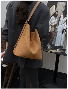 Brown faux suede tote bag shown on model over a gray blazer for casual fashion styling