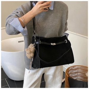 Detail of matte black crossbody tote bag featuring a silver twist lock and bear charm